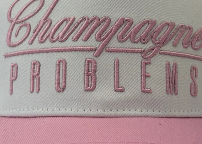 Cap with 'Champagne Problems' text on a white background
